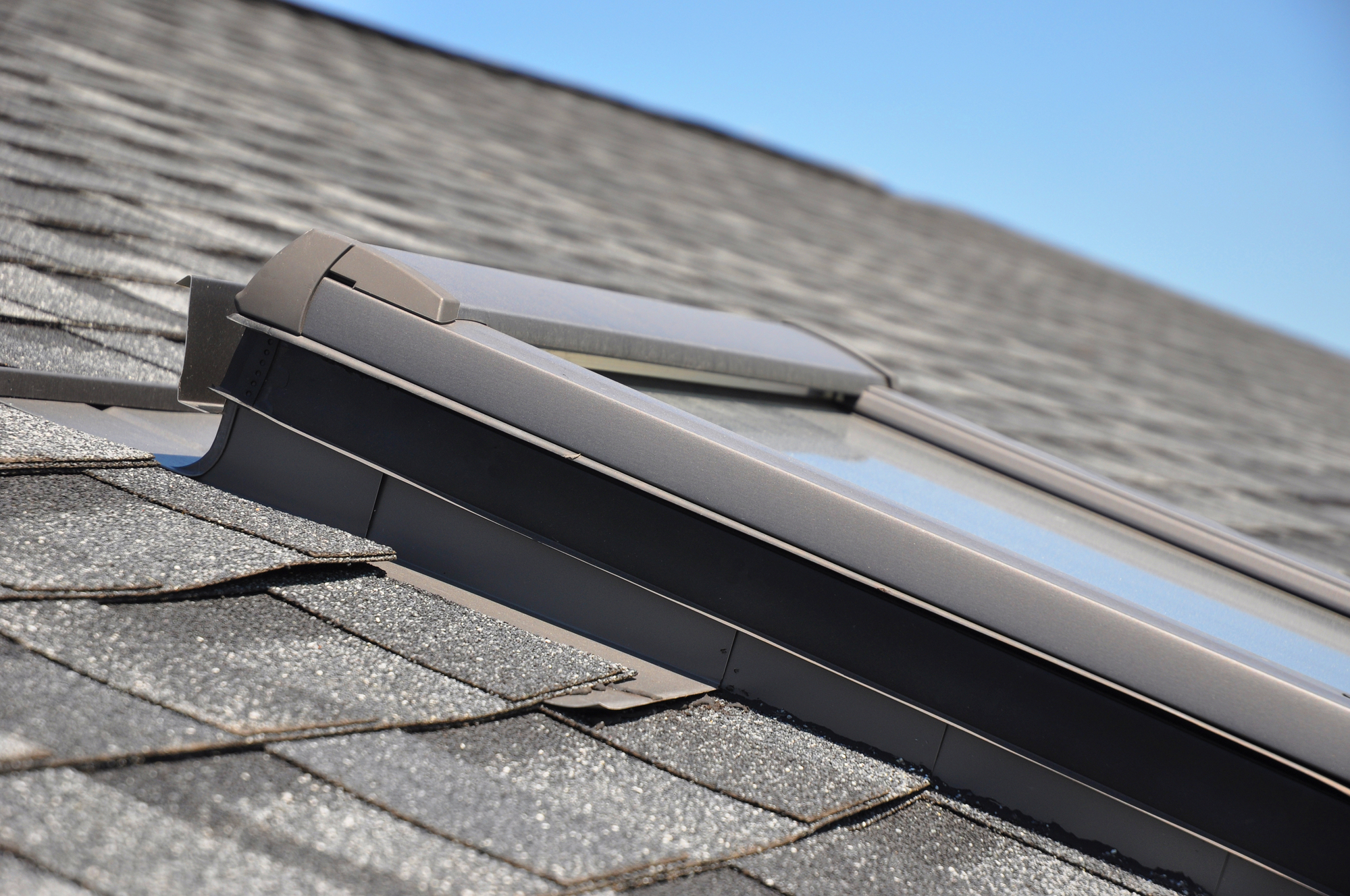 Roof window, skylights with closeup focus on bitumen-based waterproofing membrane areas.